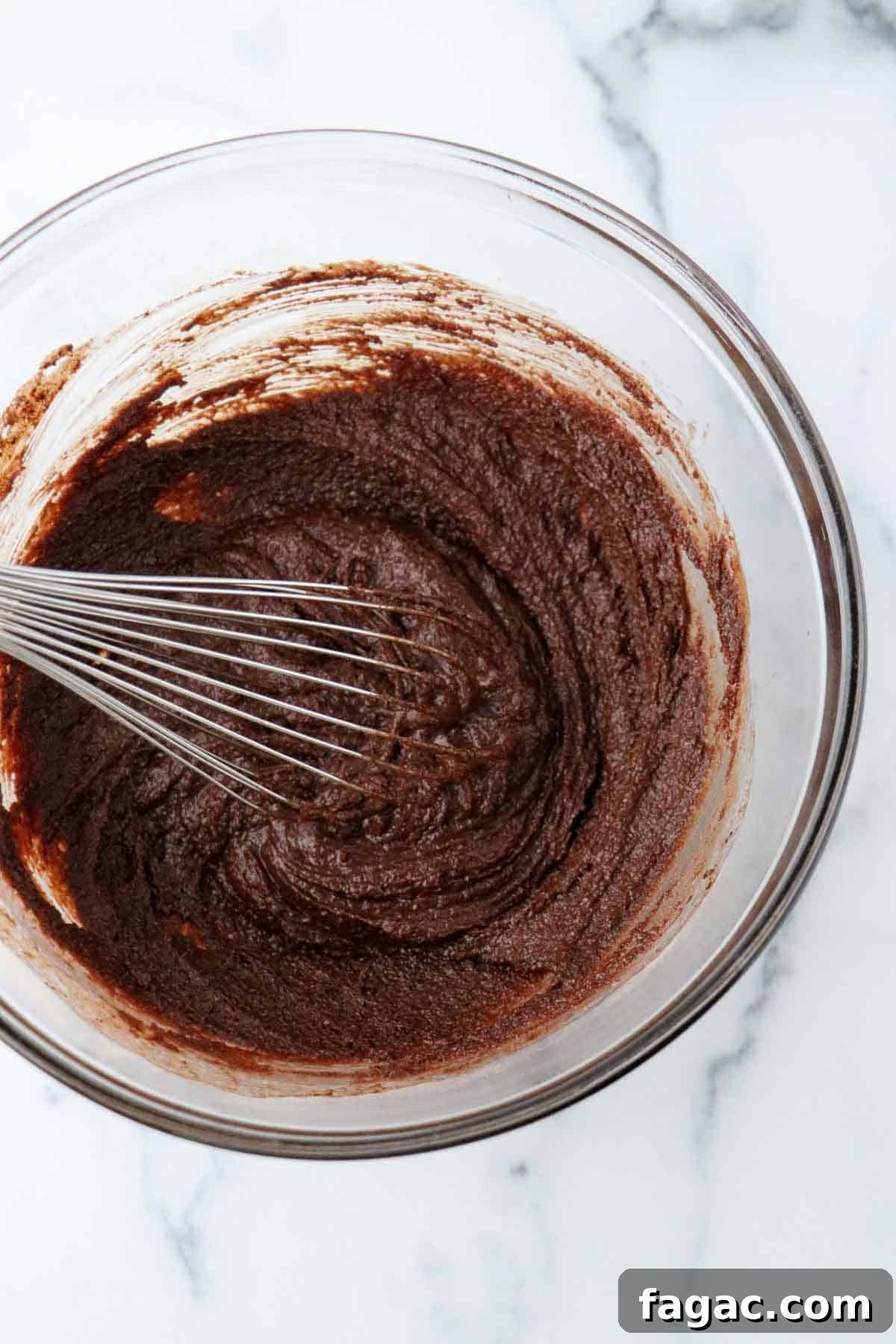 Authentic Swedish Kladdkaka: Gooey Sticky Chocolate Cake Recipe 5 Chocolate cake batter in a glass bowl with a whisk.