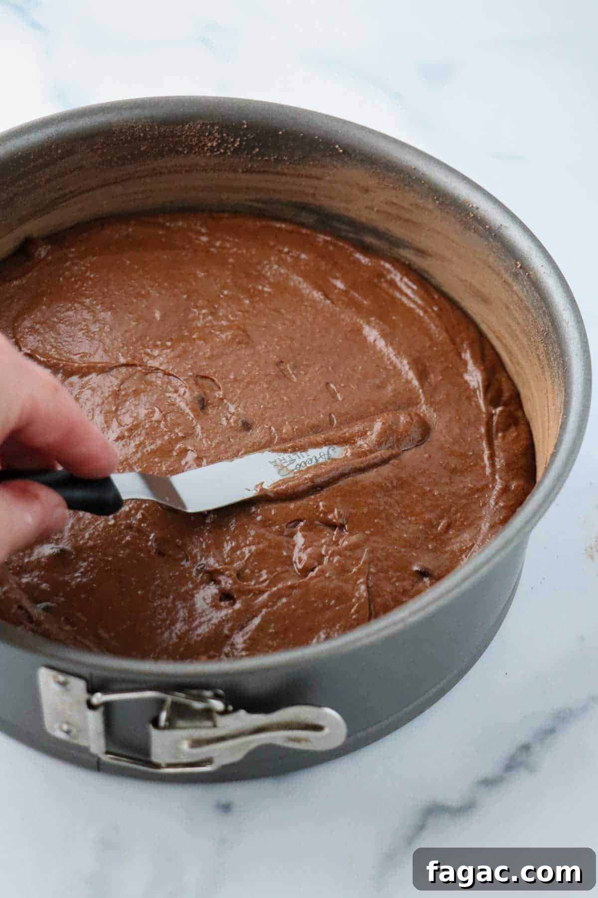 Authentic Swedish Kladdkaka: Gooey Sticky Chocolate Cake Recipe 8 Person spreading kladdkaka batter into a springform pan.