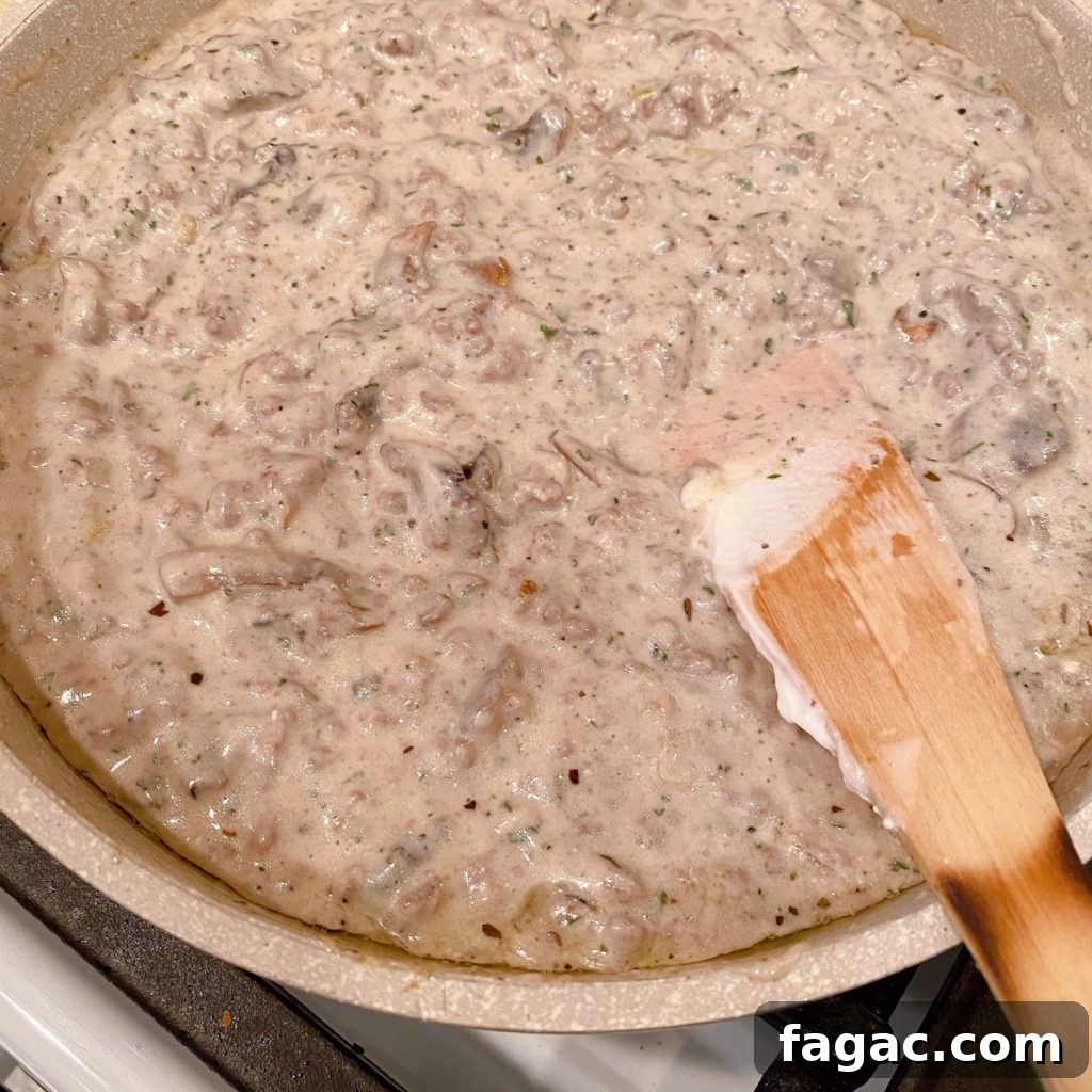 Quick Ground Beef Stroganoff Recipe for Weeknights 6 Hamburger gravy for beef stroganoff in skillet simmering on stove top.