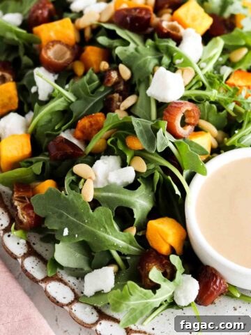 Arugula salad with squash, feta sheet, pine nuts and dates on a plate.