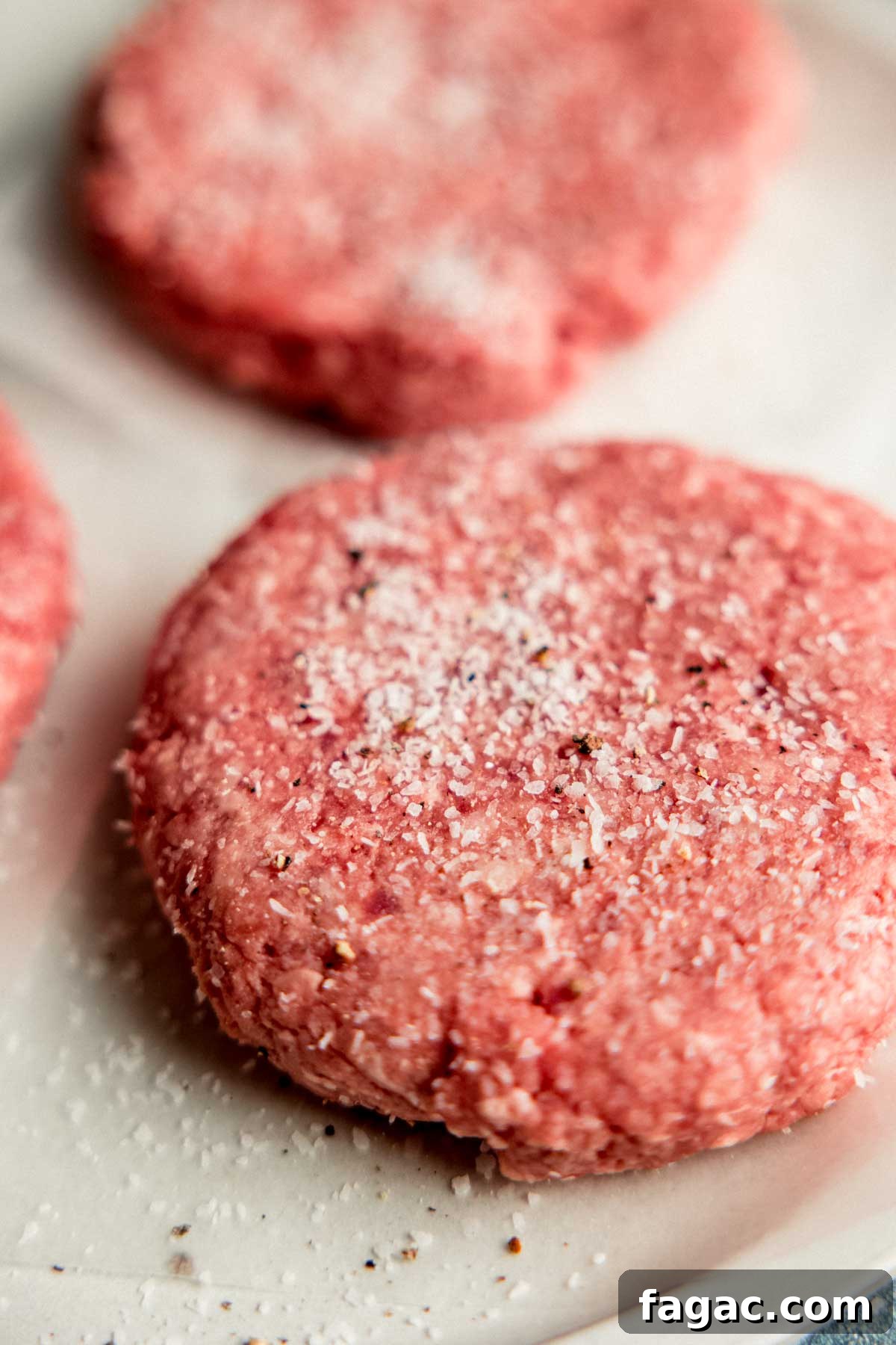 Ground beef burger patties liberally seasoned with salt and pepper.