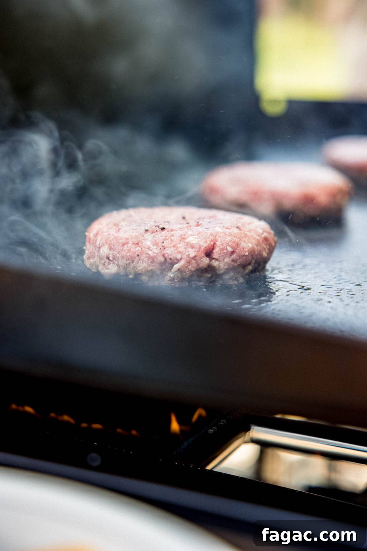 Sizzling hamburger patties cooking on a Blackstone griddle.