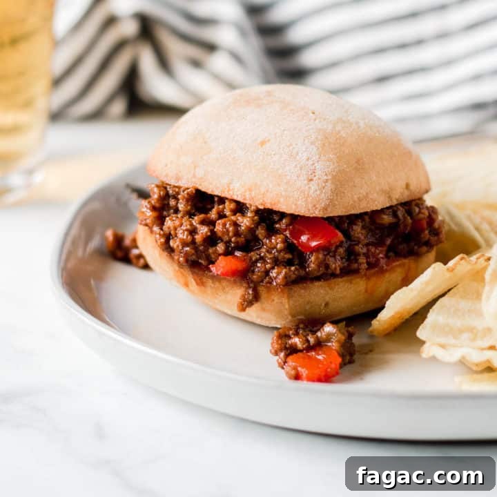 Sloppy Joe sandwich in front of blue pot and striped towel.