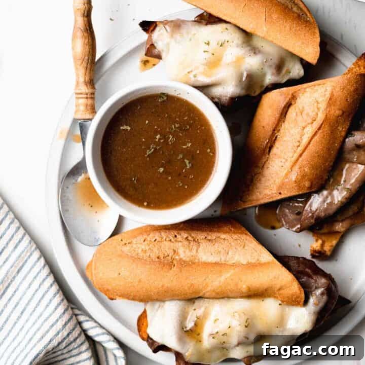 Gluten free French dip sandwiches with melted cheese and au jus dips on top next to a cup of au jus.