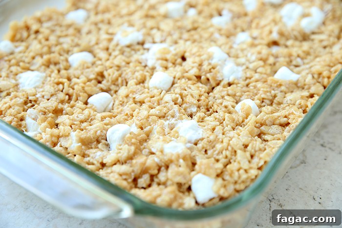 The corner of a glass 9x13 baking dish of peanut butter Rice Krispie treats.