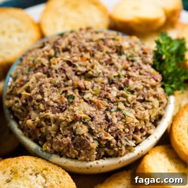 A bowl or artichoke and olive spread surrounded by toasted baguette.
