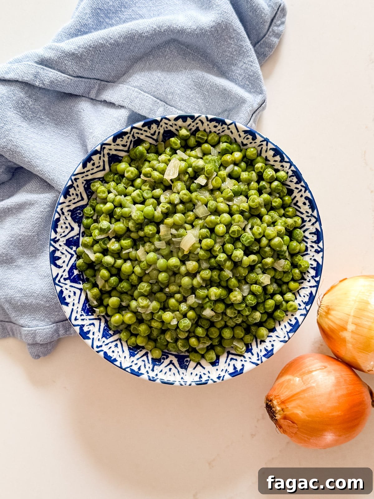 Creamy Garlic Green Peas with Parmesan 3 An overhead image of a bowl of green peas and onions.