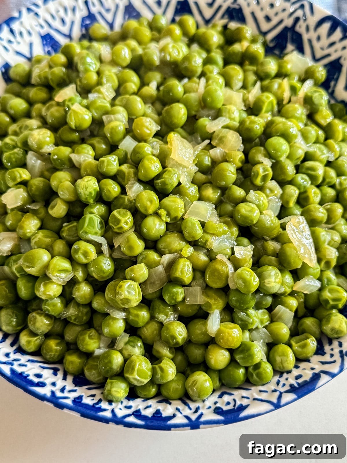 Creamy Garlic Green Peas with Parmesan 7 A close up image of peas and onions in a bowl.