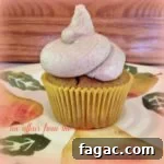 Side view of a single pumpkin cupcake with cinnamon buttercream frosting on a multicolored plate.