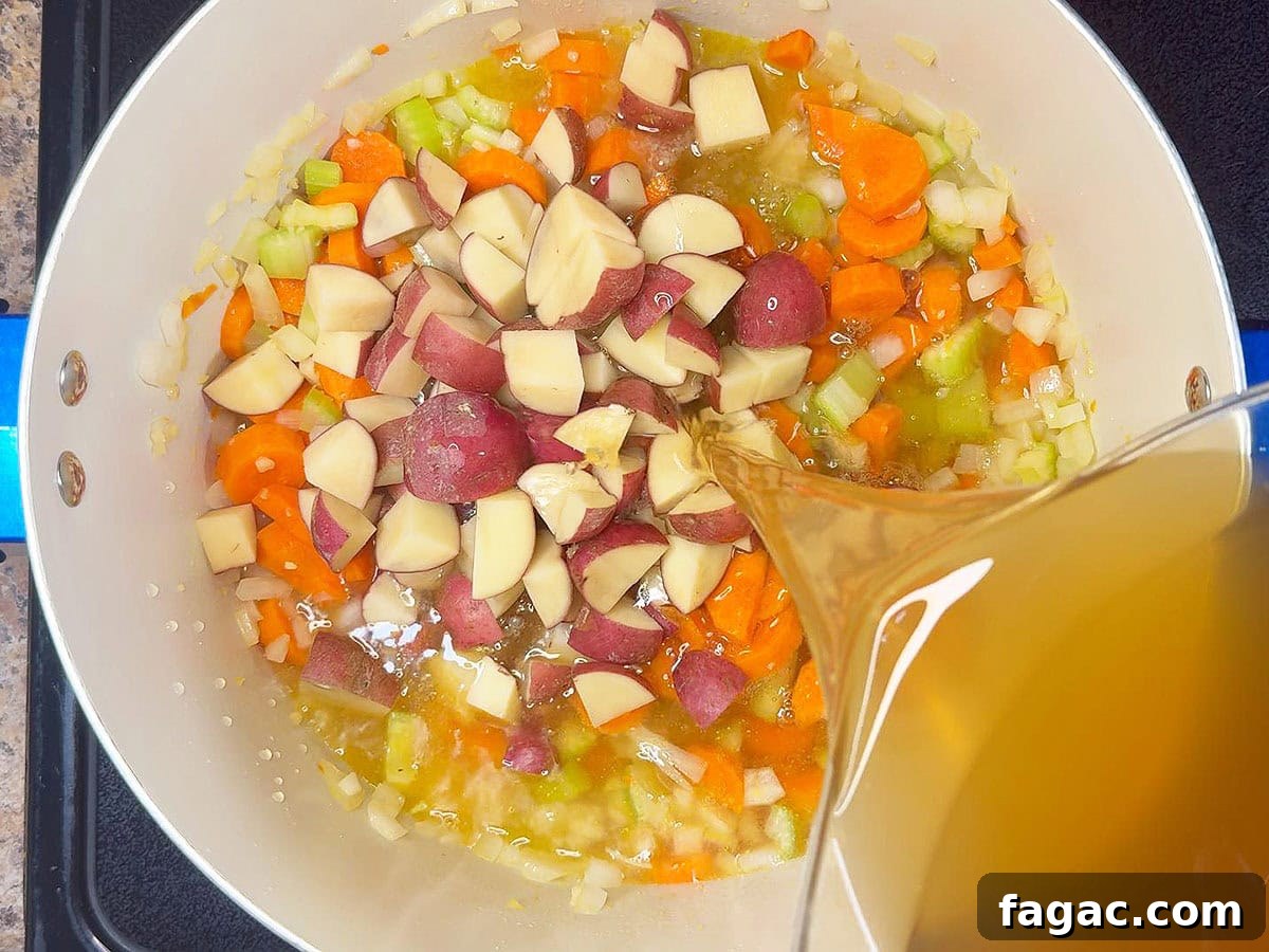 Creamy Potato and Sweet Corn Chowder Recipe 5 Adding potatoes and chicken stock to the pot with the carrots, celery, and onions.