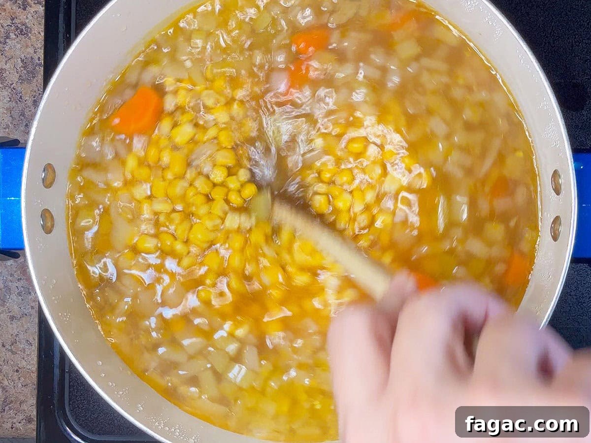 Creamy Potato and Sweet Corn Chowder Recipe 6 Stirring corn into the pot of potato corn chowder.