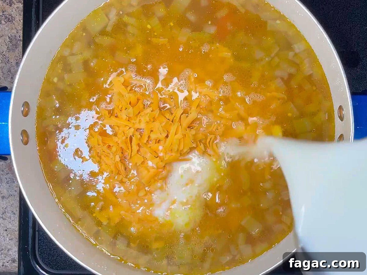 Creamy Potato and Sweet Corn Chowder Recipe 7 Adding cheese and milk to the pot of potato corn chowder.