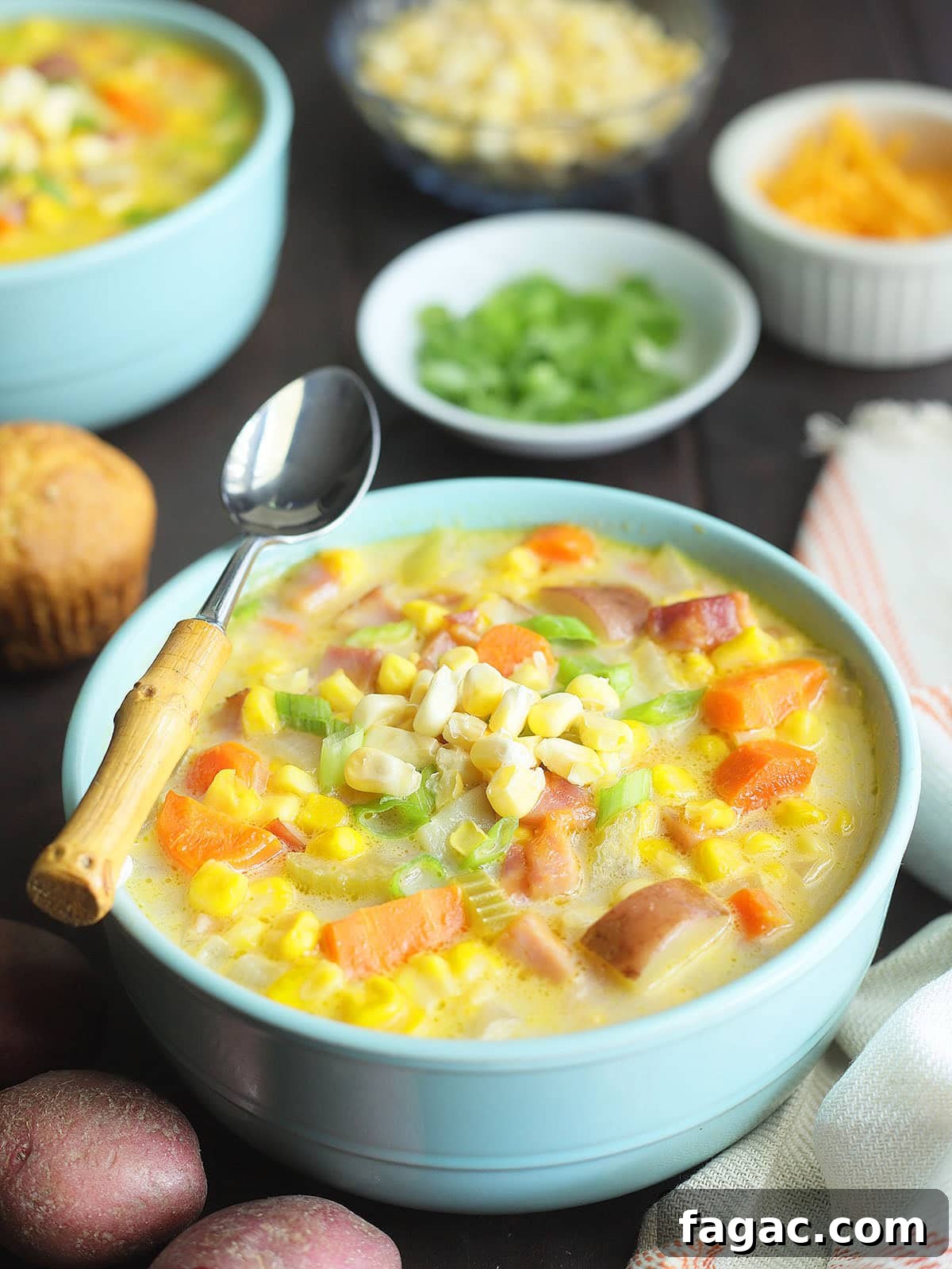 Creamy Potato and Sweet Corn Chowder Recipe 8 Two bowls of potato corn chowder with dishes of green onions, corn and cheese to the side.