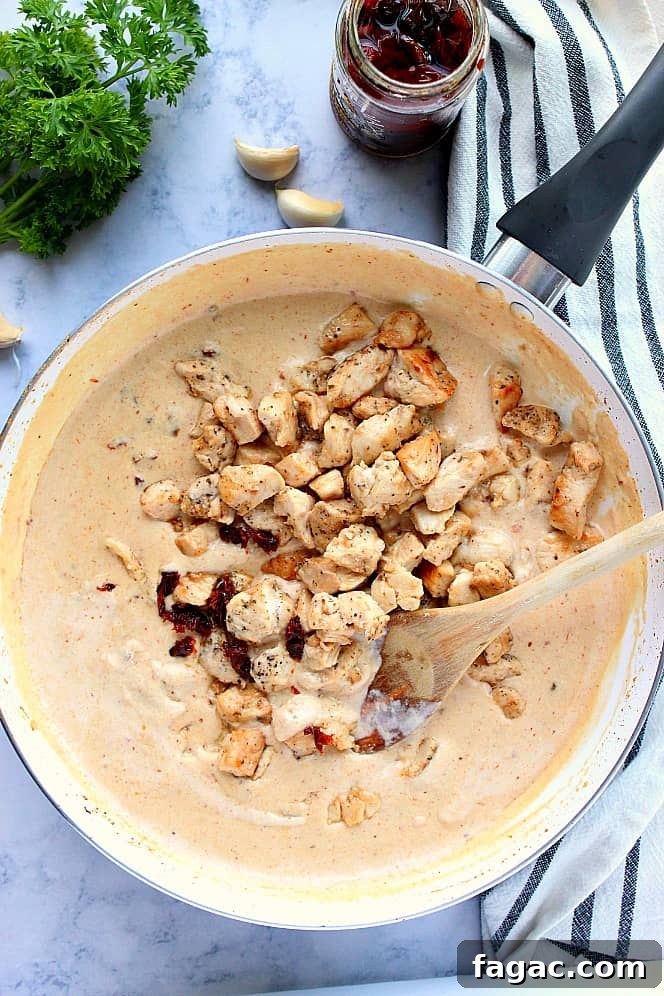 Overhead shot of creamy Alfredo sauce in skillet with cooked chicken.