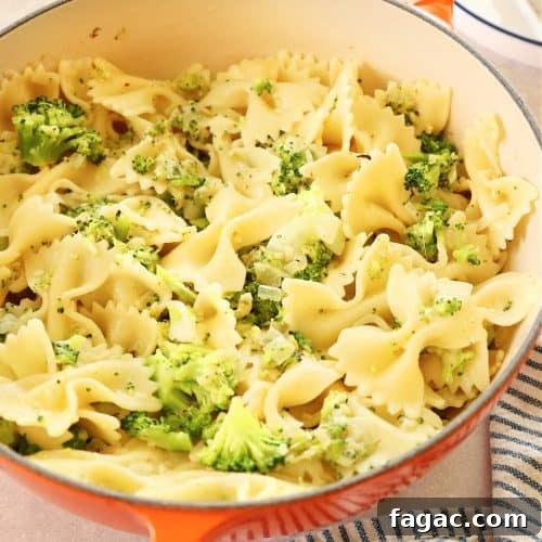 Pasta with broccoli in an orange pan.