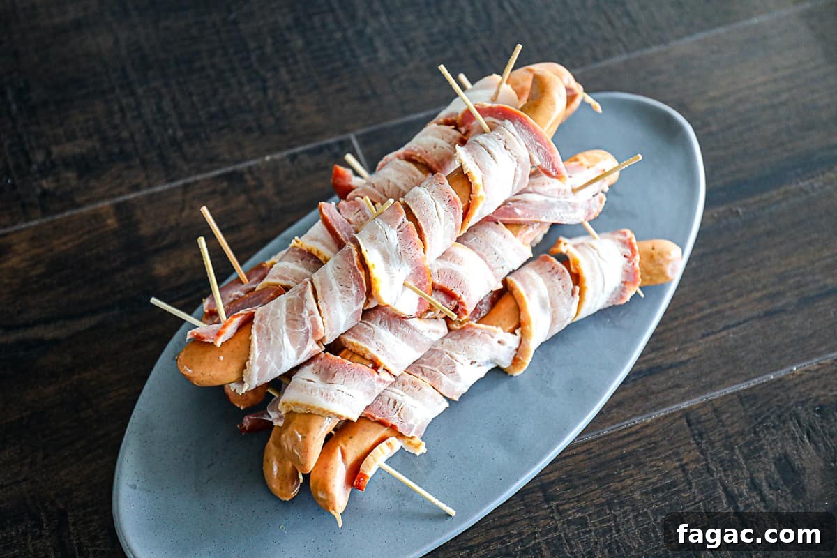 Crispy Bacon-Wrapped Hot Dogs: Air Fryer, Oven & Grill Methods 4 Assembled hot dog wrapped in bacon with toothpicks.