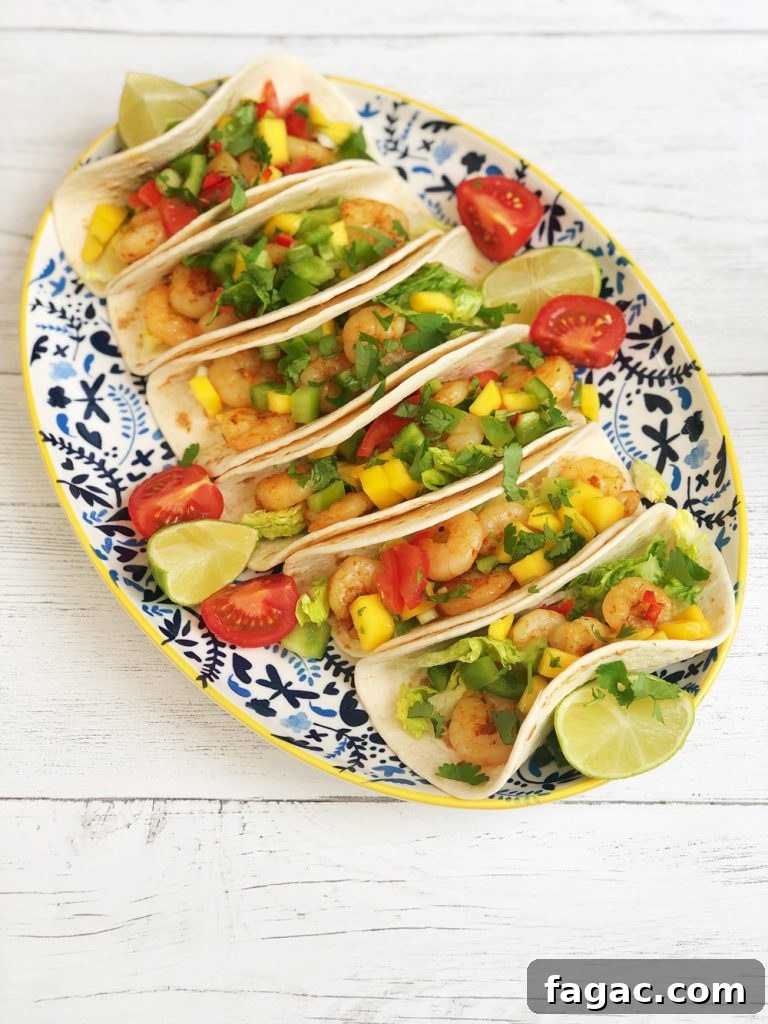Homemade Cajun prawn tacos with spicy mango salsa garnished with lime wedges and tomatoes.