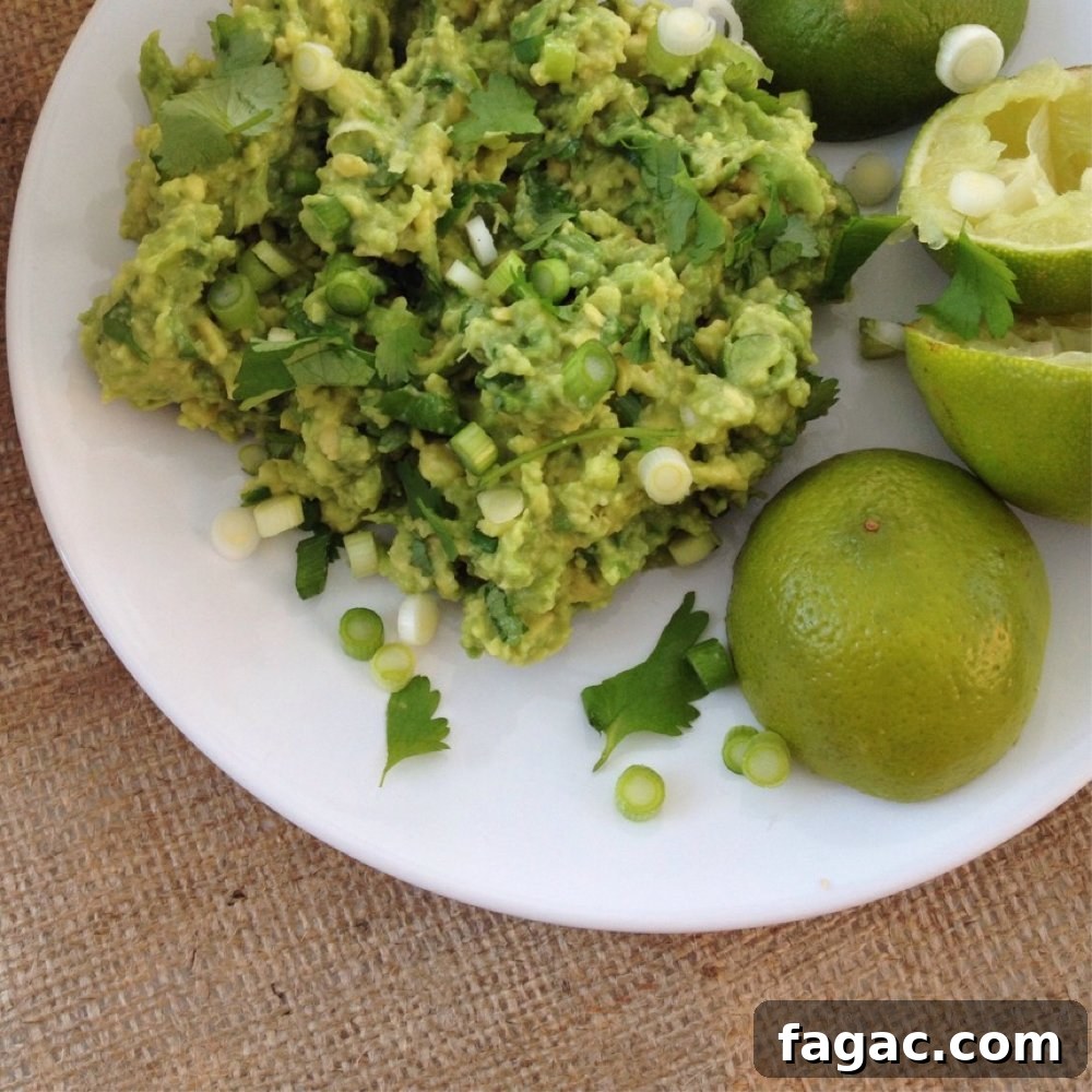 white plate with pile of homemade guacamole alongside some lime halves