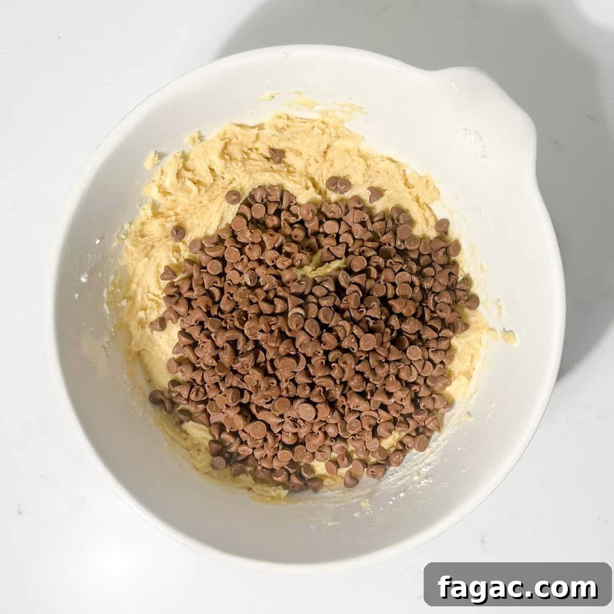 Chewy Chocolate Chip Cookies Without Brown Sugar: Crisp Edges, Soft Center 11 Adding the chocolate chips to the batter in a large white bowl.