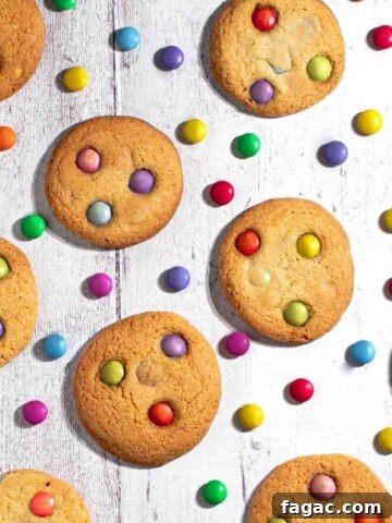 Smartie cookies on a white background with scattered Smarties between the cookies.