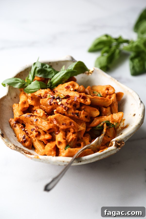 Gluten-Free penne with low FODMAP vodka sauce in a bowl with basil garnish and spoon