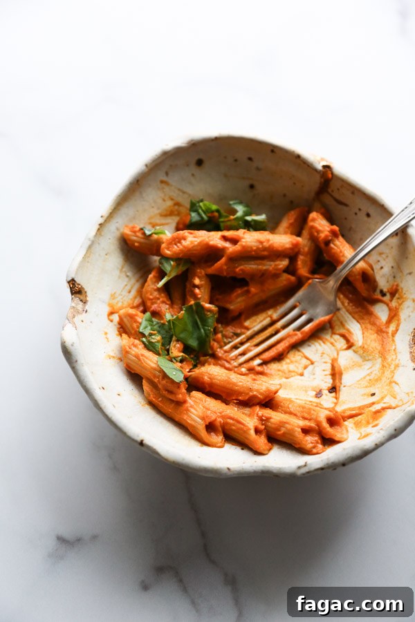 Gluten-Free penne with low FODMAP vodka sauce in a bowl half eaten with fork