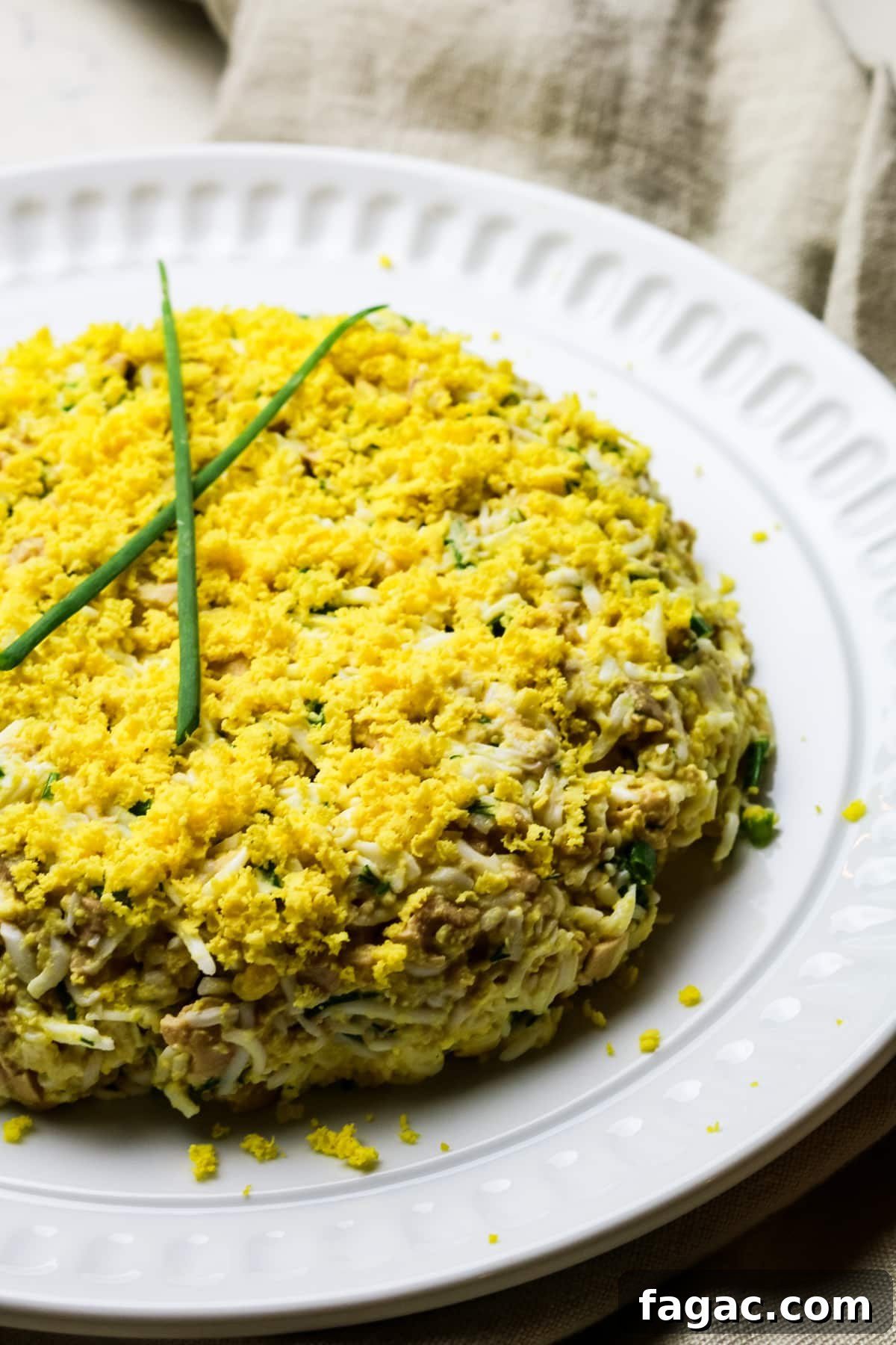 Cod Liver and Egg Salad Recipe: Creamy, Tangy Seafood Salad 2 cod liver salad with eggs on a white plate with green onion sprigs on top.