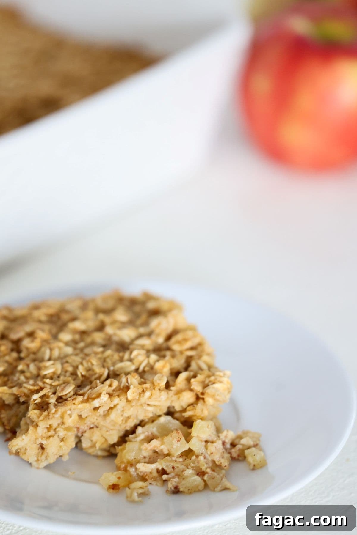 Apple Cinnamon Baked Oatmeal Recipe for Cozy Breakfasts 2 One piece of baked oatmeal with apples and cinnamon on a white plate.