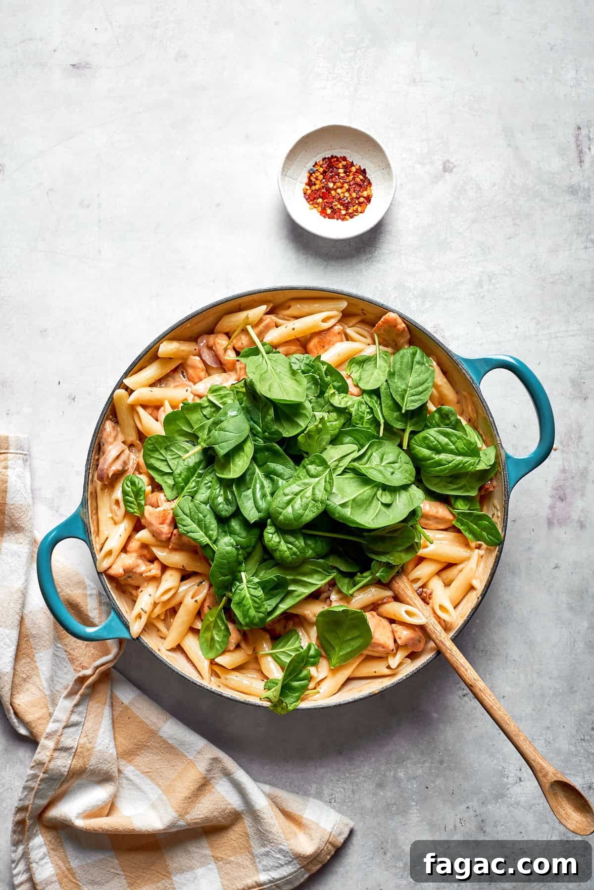 Marry Me Chicken Pasta Recipe — Creamy Tomato Garlic Pasta with Chicken 3 Spinach leaves added to a skillet of marry me chicken pasta.