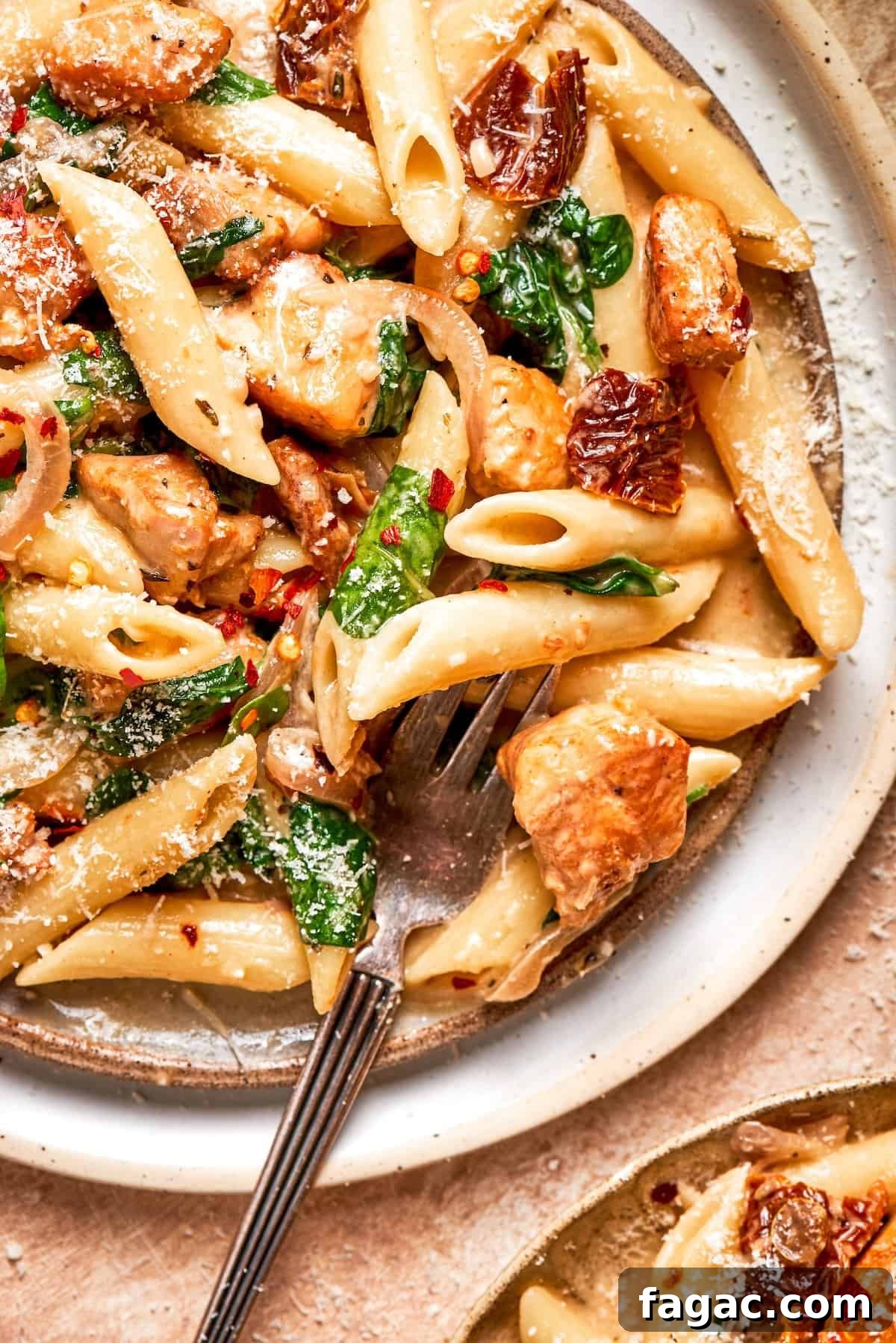 Cheesy, marry me chicken pasta features tender bites of chicken swirled in a creamy sauce along with sundried tomatoes and pasta. A fork rests in a plate of marry me chicken pasta.