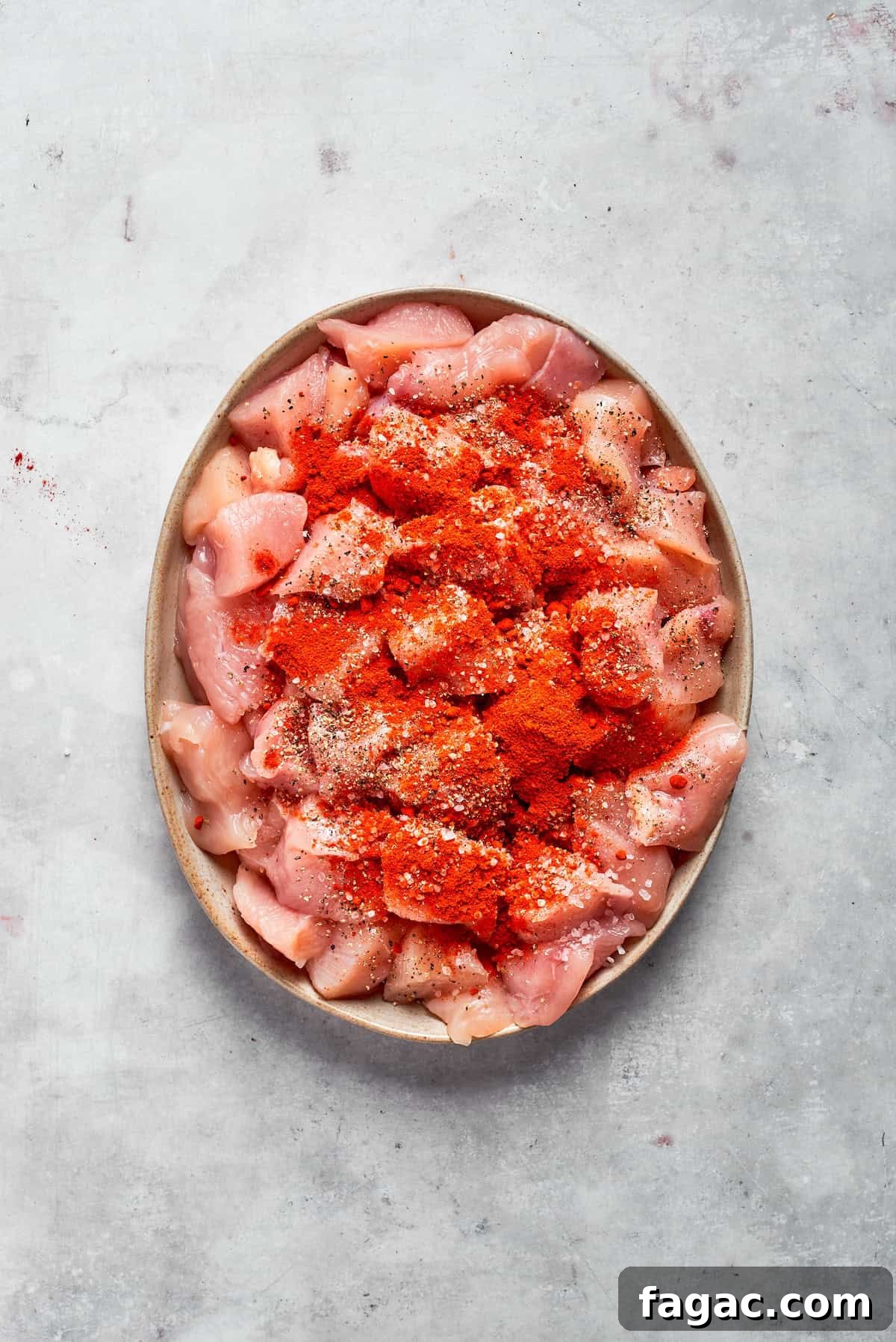 Season chicken. Chicken pieces with seasonings on a plate.