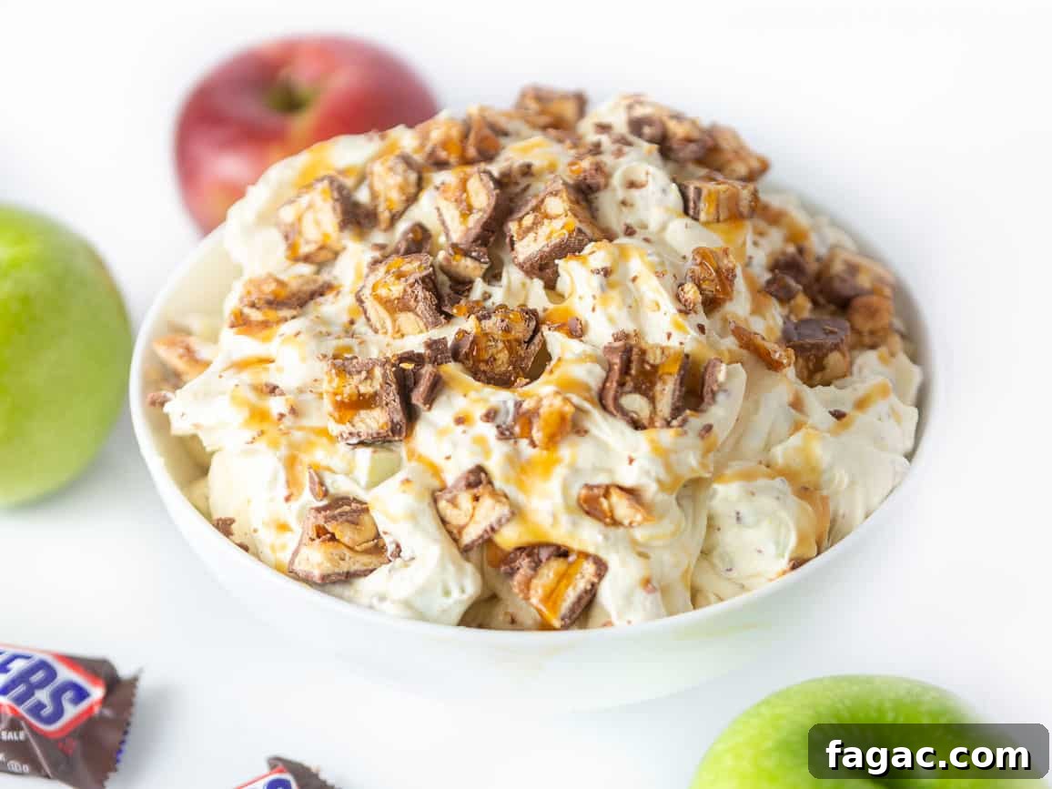 Apple Snickers Salad Recipe: Crunchy Caramel Apple Dessert Salad 3 Bowl of creamy apple snickers salad dessert, topped with chopped snickers candy bars, apples, and caramel sauce
