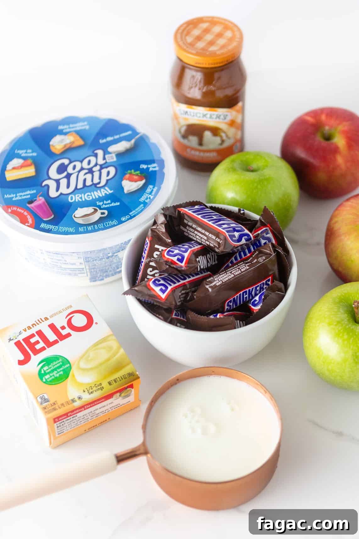 Apple Snickers Salad Recipe: Crunchy Caramel Apple Dessert Salad 4 Ingredients for apple snickers salad; includes bowl of snickers, cool whip, a box of instant vanilla pudding mix, milk, apples, and a jar of Smuckers caramel sauce