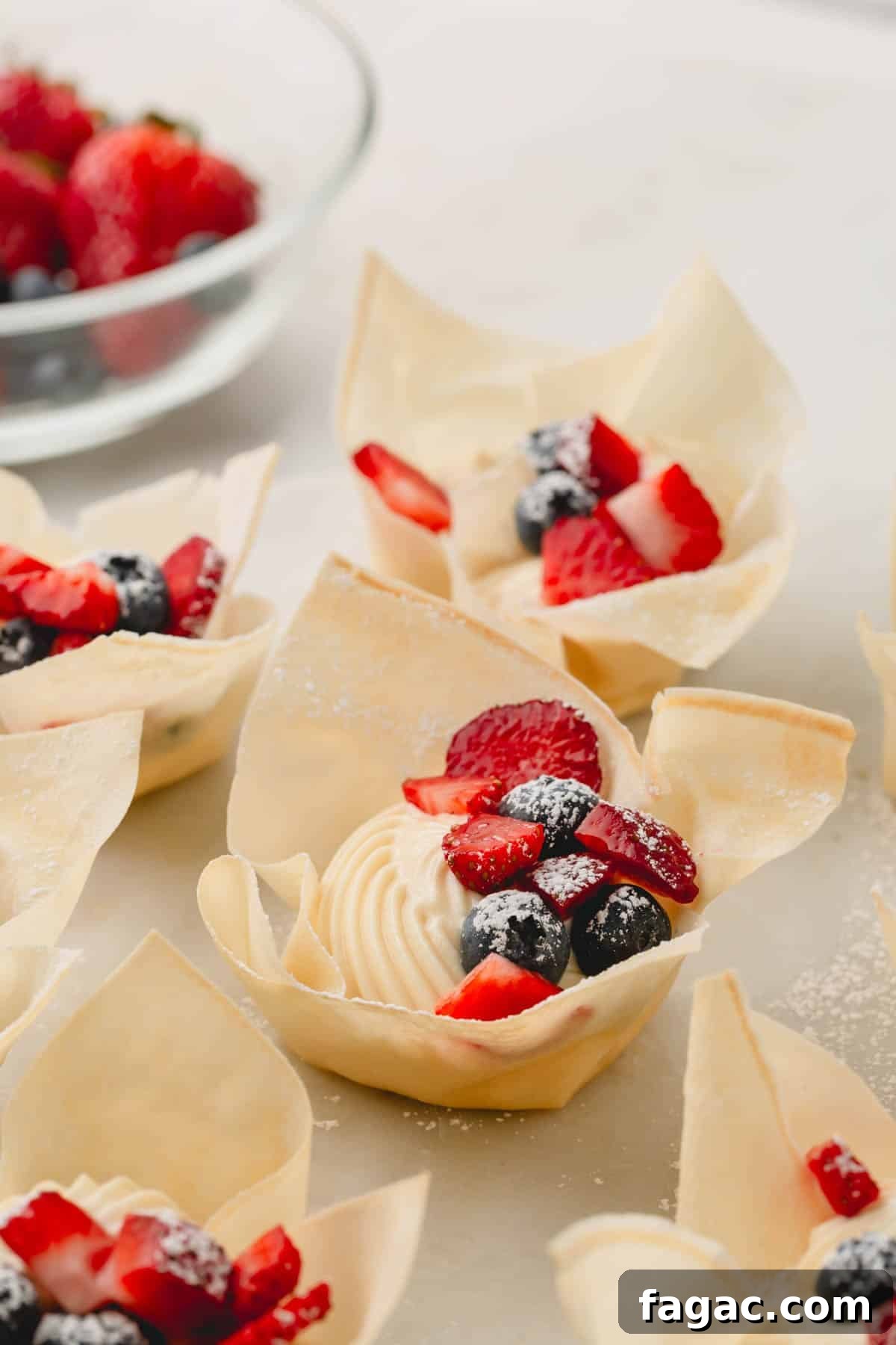 Quick Berry Tartlets: Simple Fresh Fruit Pastry Recipe 9 Mini berry tartlets topped with strawberries, blueberries, and powdered sugar.