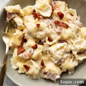 a bowl of cream cheese tortellini alfredo with a fork