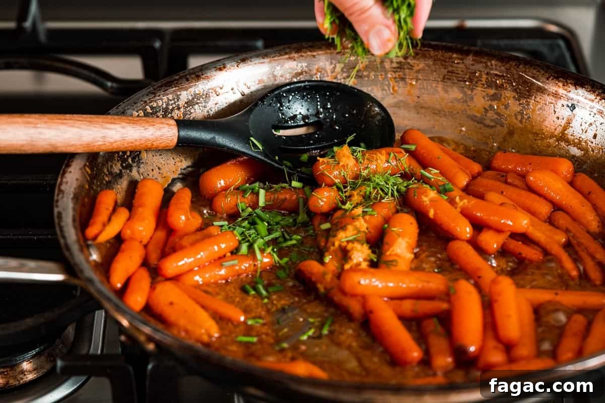 Honey-Glazed Orange Carrots with Citrus Butter Glaze 12 fresh herbs being sprinkled overtop pan of honey orange glazed carrots