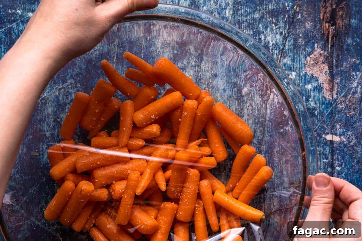 Honey-Glazed Orange Carrots with Citrus Butter Glaze 6 bowl of baby carrots with plastic wrap being applied overtop