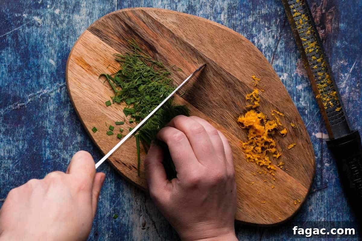 Honey-Glazed Orange Carrots with Citrus Butter Glaze 7 herbs being chopped on wooden cutting board with orange zest on the side