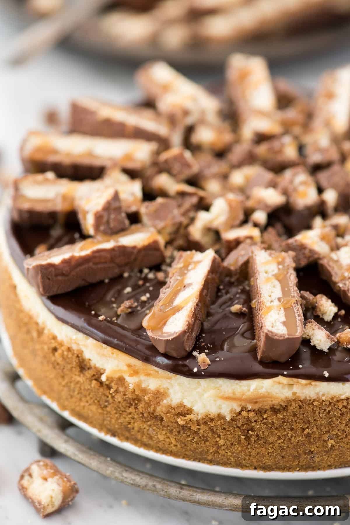 Twix cheesecake with graham cracker crust, caramel swirl and chocolate ganache Slice of Twix cheesecake