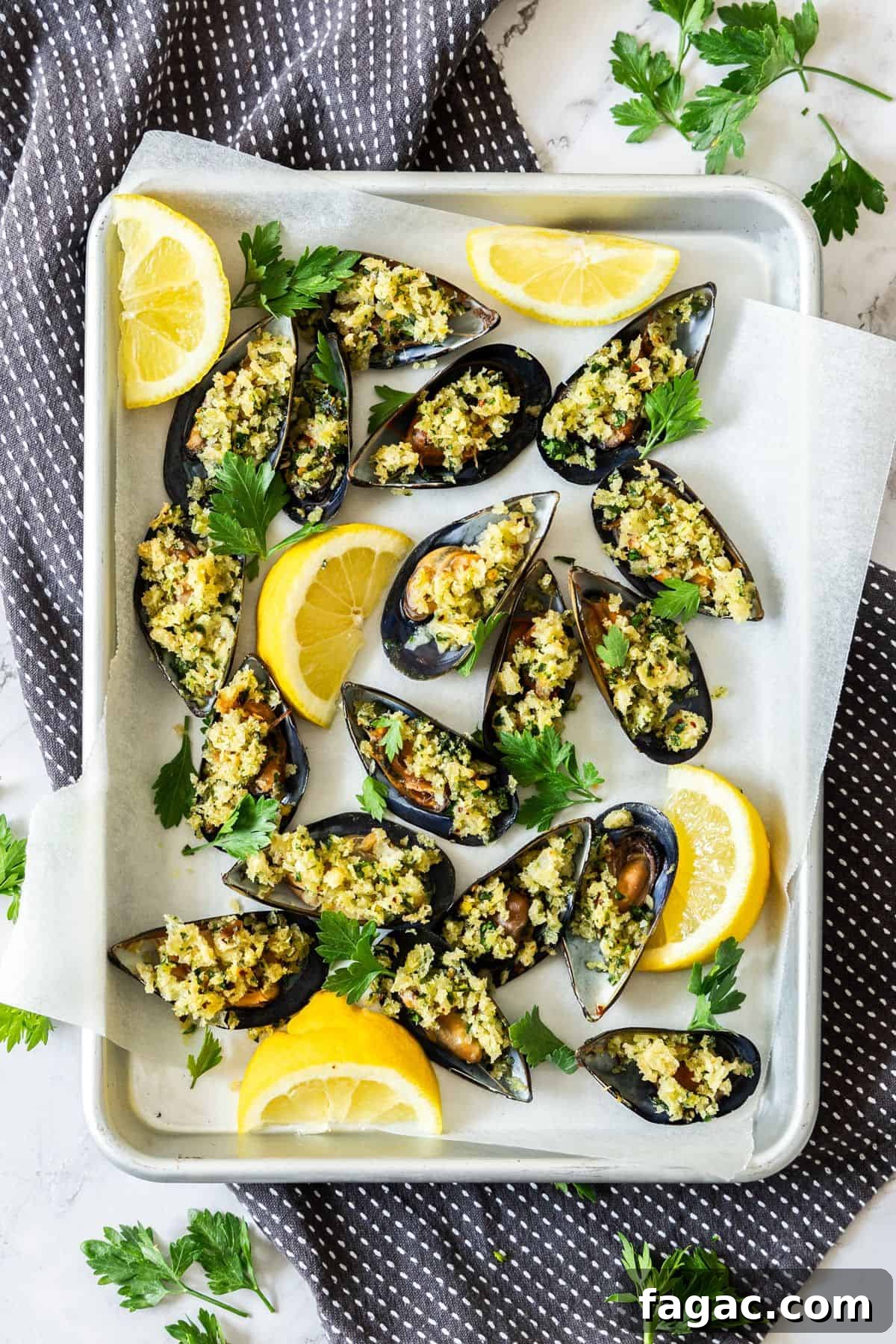 Tray of stuffed Baked Mussels, garnished with some lemon and parsley leaves.