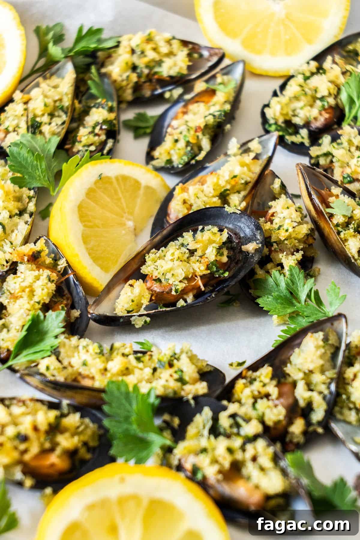 Tray of stuffed Baked Mussels, garnished with some lemon and parsley leaves.
