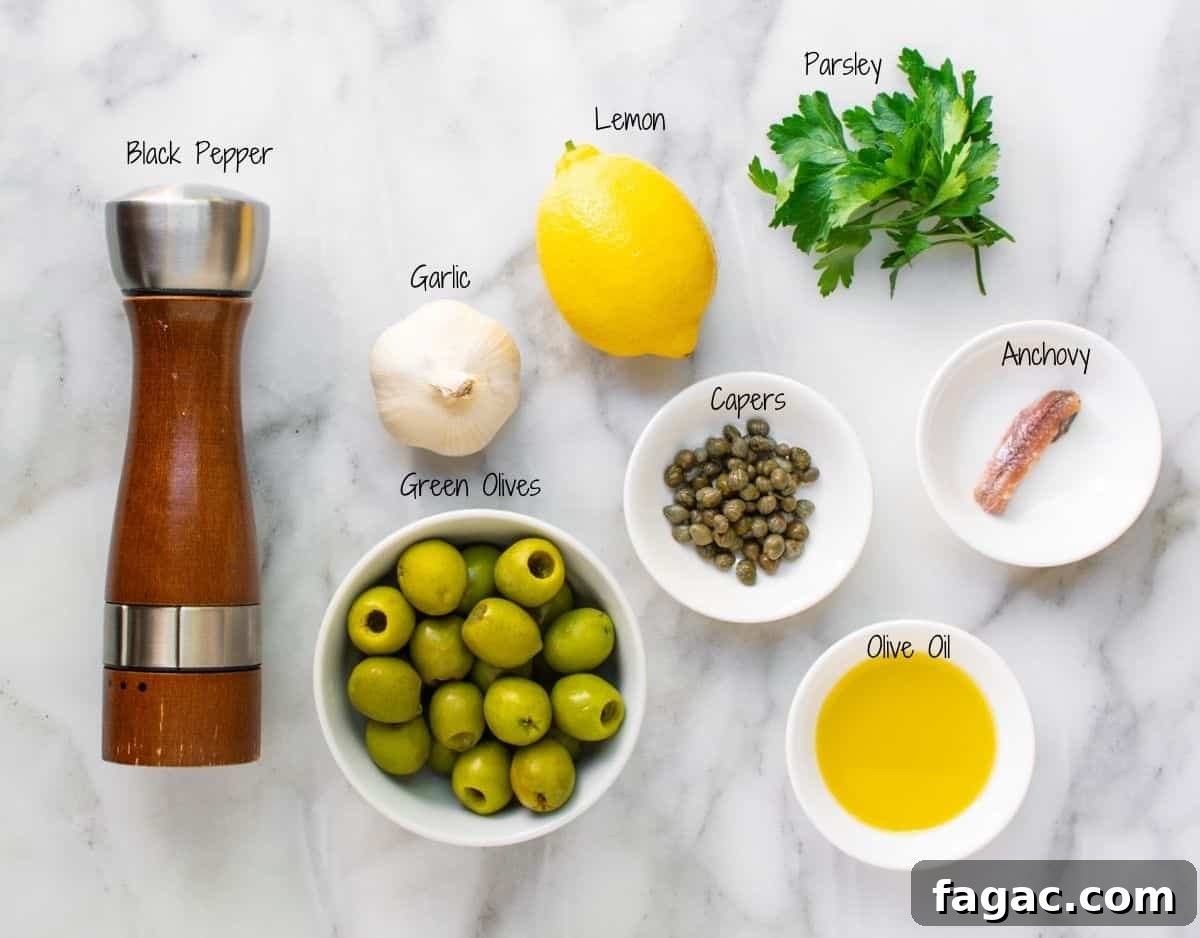 Green Olive Tapenade Ingredients on a white marble board.