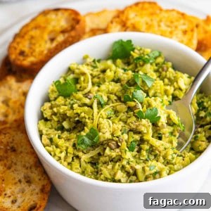 Green Olive Tapenade served in a white bowl with crostini around.