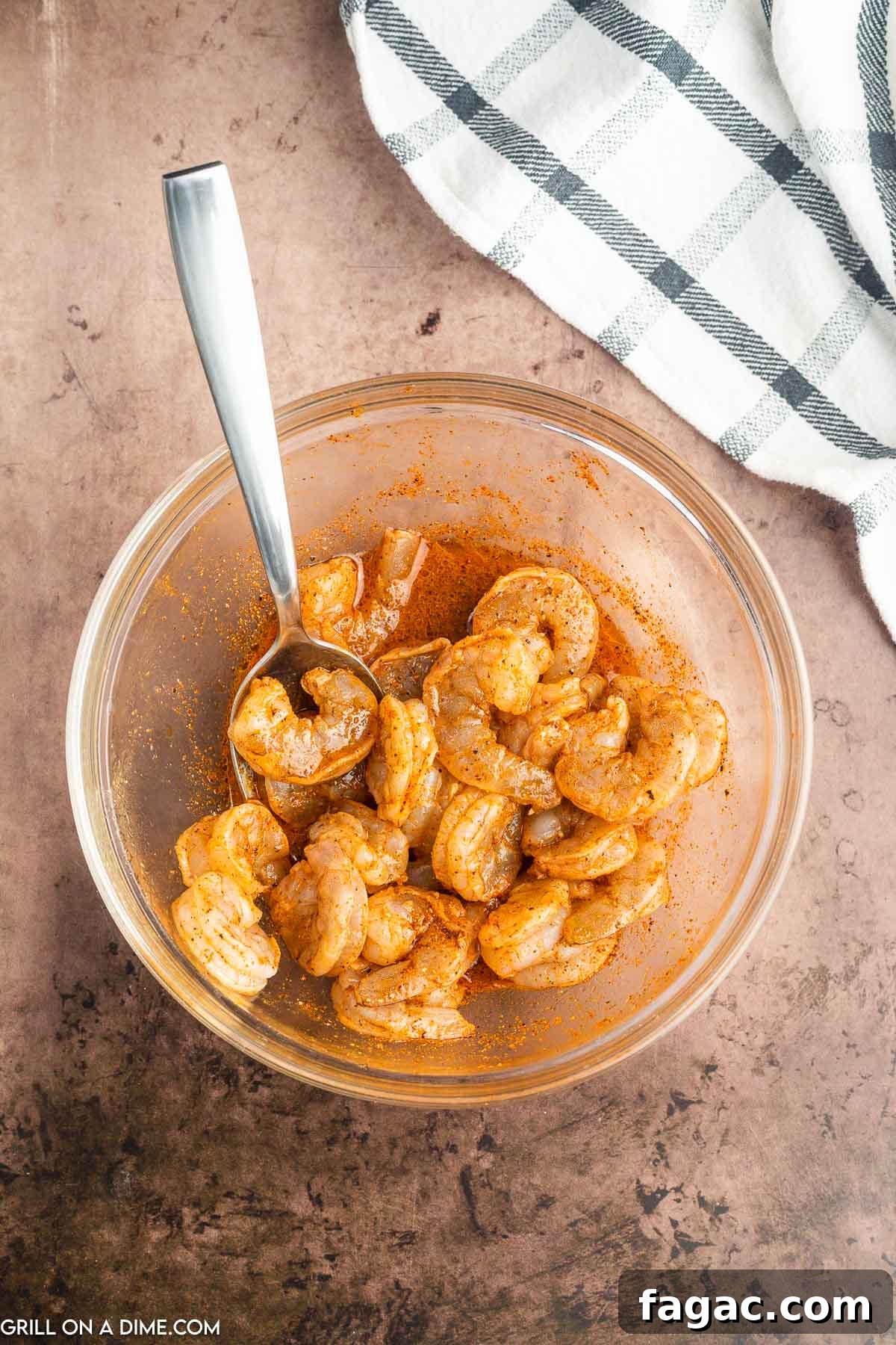 Mixing shrimp in a bowl with the seasoning with a spoon.