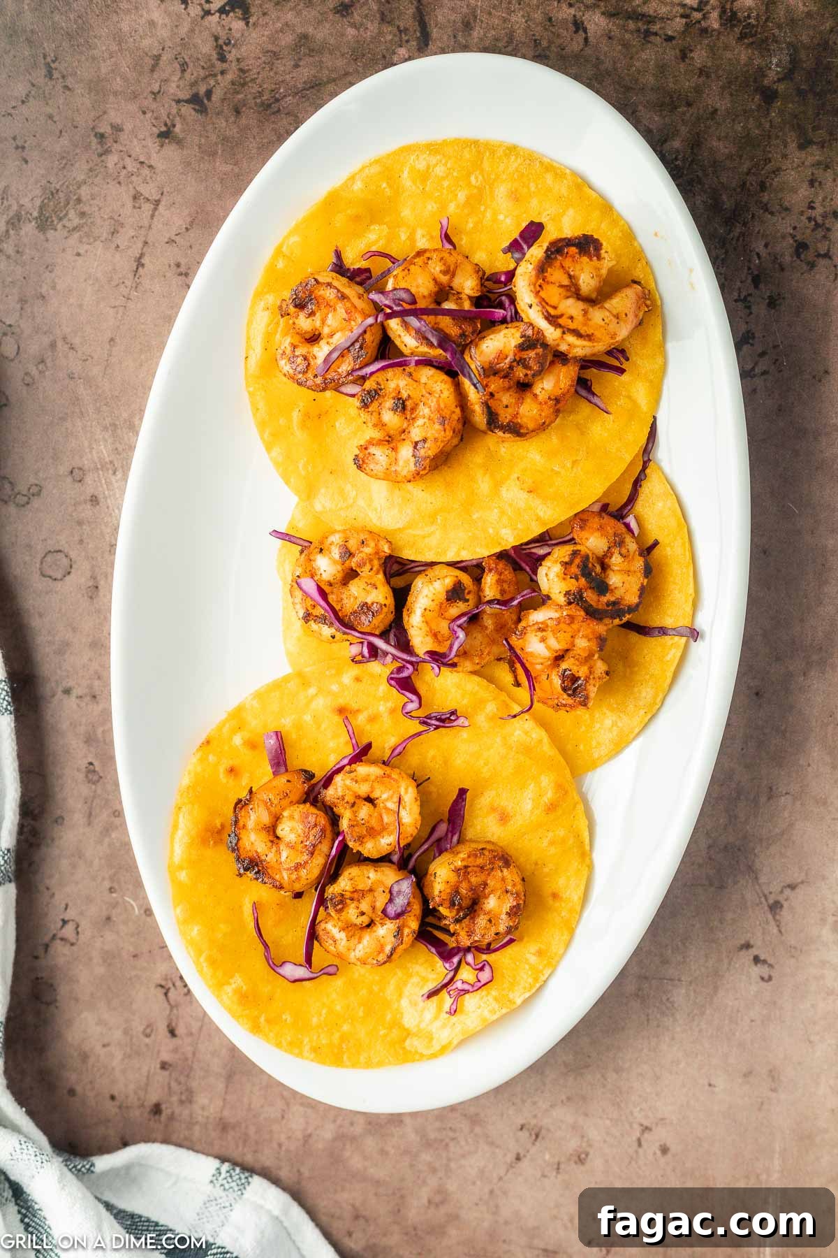 Topping corn tortillas with shrimp and with coleslaw.