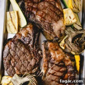 How to Grill a Tender, Flavorful Steak Every Time 12 3 grilled ribeye steaks on a baking sheet with grilled zucchini and artichokes.