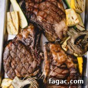How to Grill a Tender, Flavorful Steak Every Time 13 3 grilled ribeye steaks on a baking sheet with grilled zucchini and artichokes.
