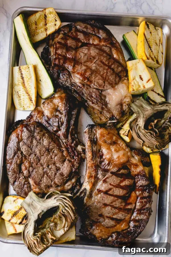 How to Grill a Tender, Flavorful Steak Every Time 3 3 grilled ribeye steaks on a baking sheet with grilled zucchini and artichokes.