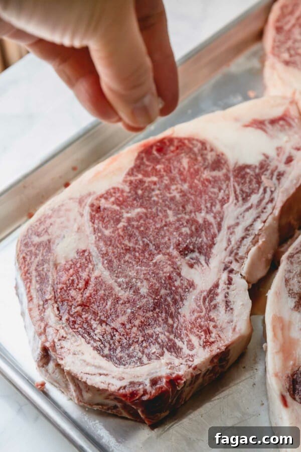 How to Grill a Tender, Flavorful Steak Every Time 7 Raw ribeye being salted.