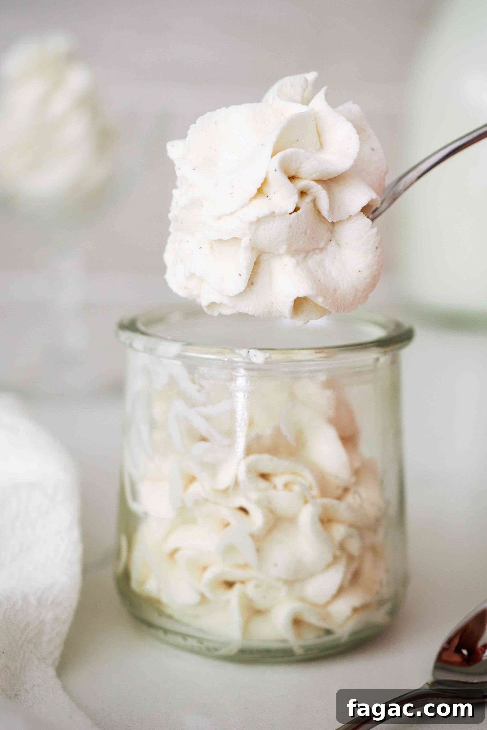 Silky Vanilla Whipped Cream Recipe for Desserts and Toppings 2 A spoonful of vanilla whipped cream over a full jar.